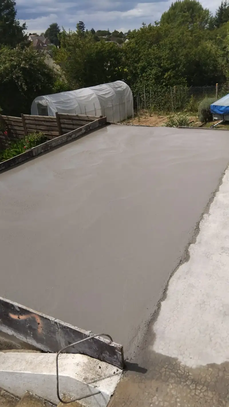 Dalle béton fraîchement coulée et tirée à la règle dans son coffrage bois