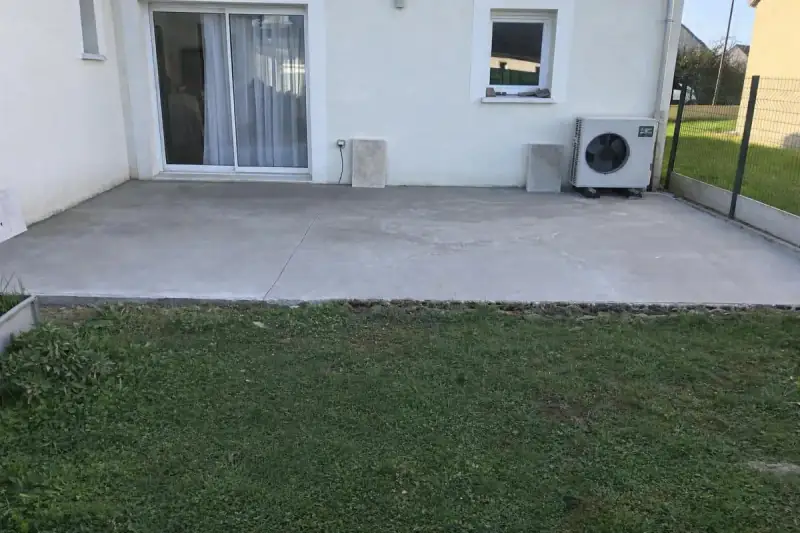Dalle de terrasse en béton coulée à l'arrière d'une maison, au niveau de la baie vitrée