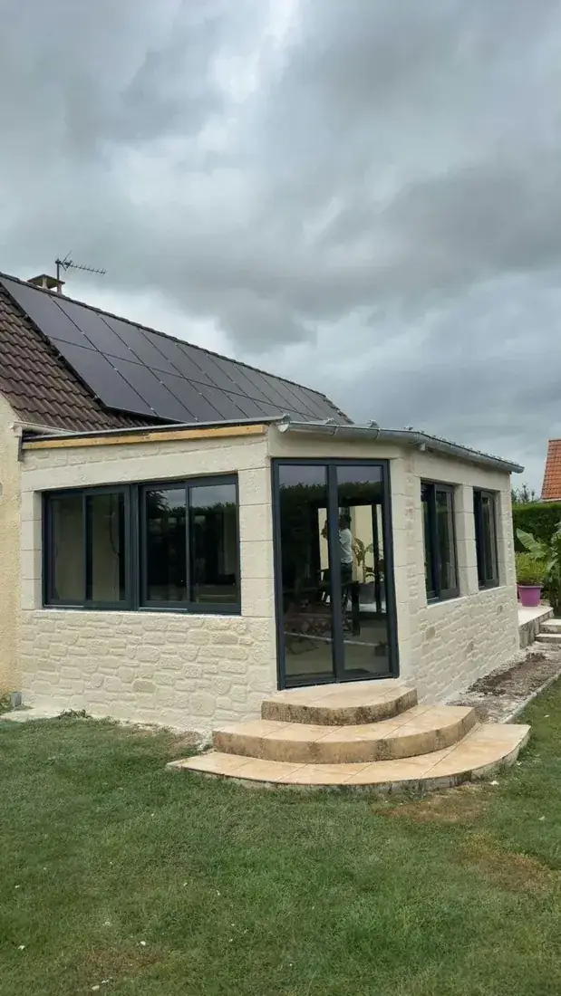 Extension de maison avec grandes baies, façade en enduit décor pierre et encadrements