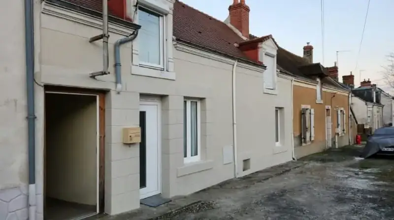 Façade de maison de ville enduite avec encadrements de fenêtres et chaînes d'angle