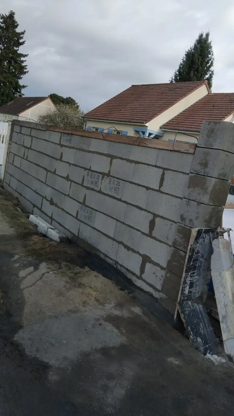Mur en parpaing en cours d'élévation avec coffrage et ferraillage du chaînage horizontal