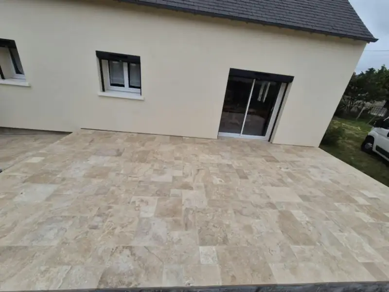 Grande terrasse en dallage travertin posé en opus romain le long d'une maison